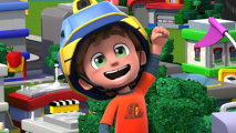 A young boy in a red shirt and blue helmet is smiling and standing in front of a town.