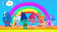 Colourful trolls, with big hair, standing in front of a blue sky and a rainbow.
