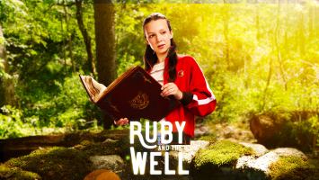 A teenage girl with long hair, wearing a red jacket is holding a book in the middle of a forest in from of a well.