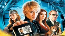 A blond young man holding up a secret agent card with three other people behind him.