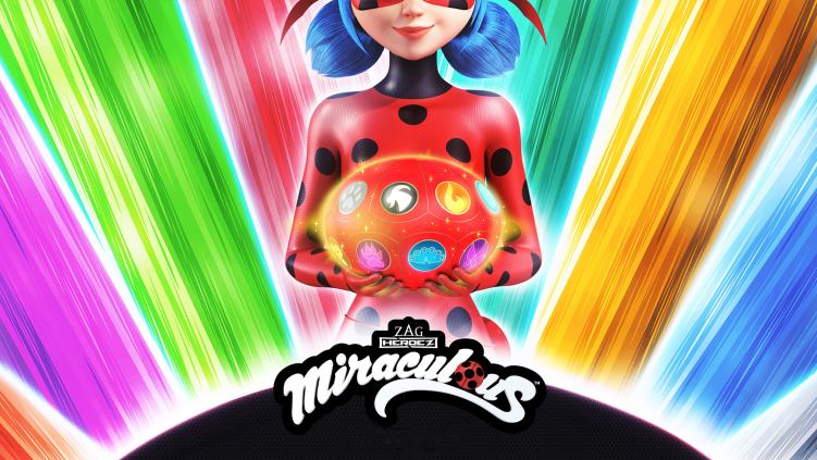 A girl dressed in a ladybug suit is holding a glowing red ball in her hands and standing in front of a rainbow background.